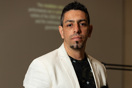 A man in white jacket in front of video art installation