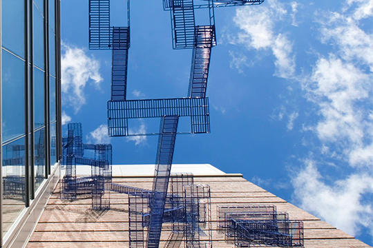 blue interwining staircases extend between two buildings