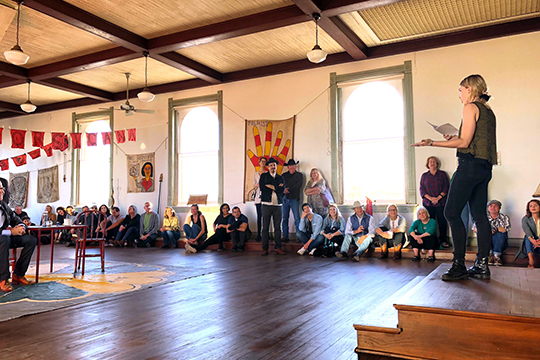 woman stands on stage at open house of artist studios in corsicana