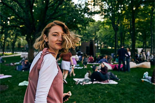 teen girl with white shirt and pink dress looks at camera while in the nasher sculpture garden