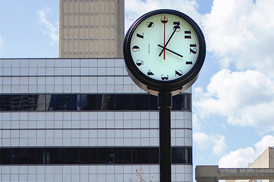 clock sculpture with time as one fifty. face of the clock is rotated so twelve is skewed to the right in the three oclock position